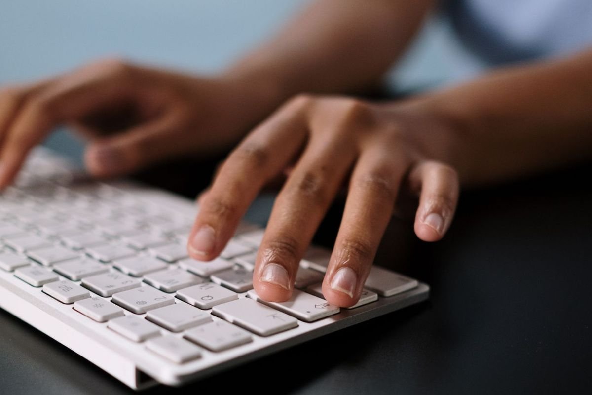 Hands typing on a white keyboard at a desk