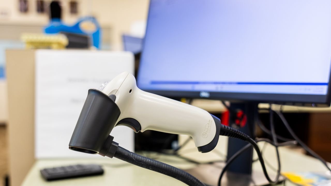 Barcode scanner resting on an office desk beside a monitor