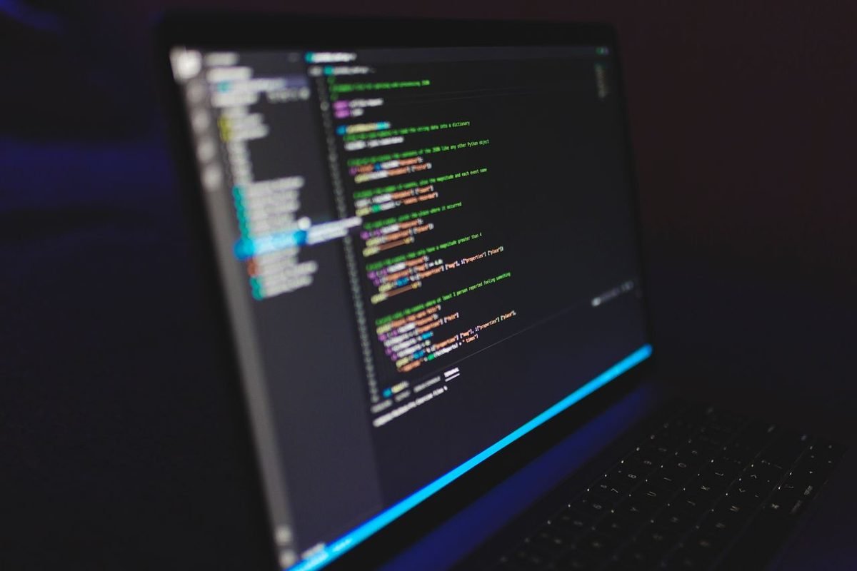 Angled laptop showing code in a dark workspace