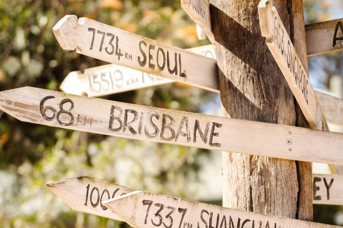 Wooden signpost with hand-painted distances to Seoul, Brisbane and Shanghai