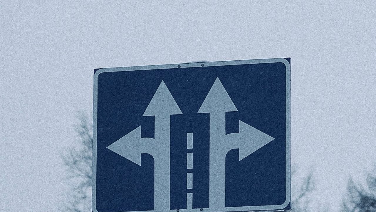 Blue road sign with arrows pointing in different directions
