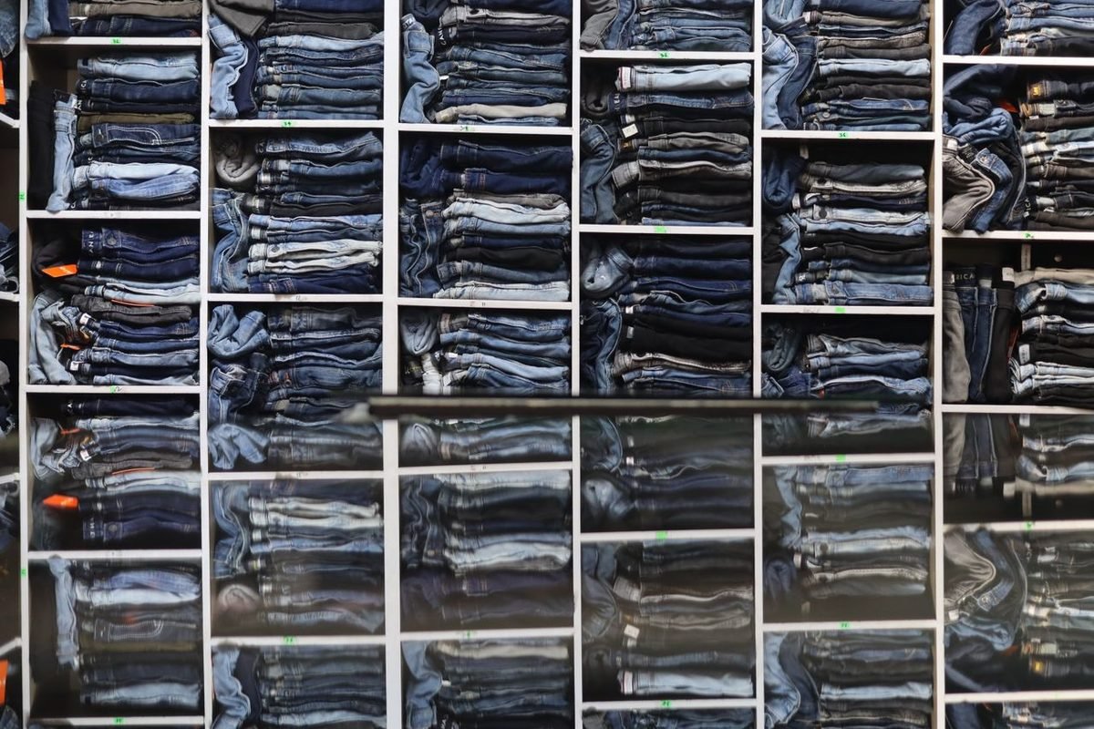 Folded jeans stacked in rows of shelves seen from above
