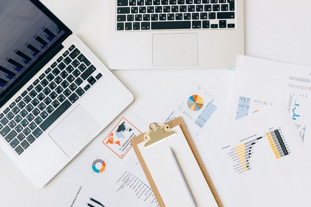 Laptops and printed performance charts spread across a desk