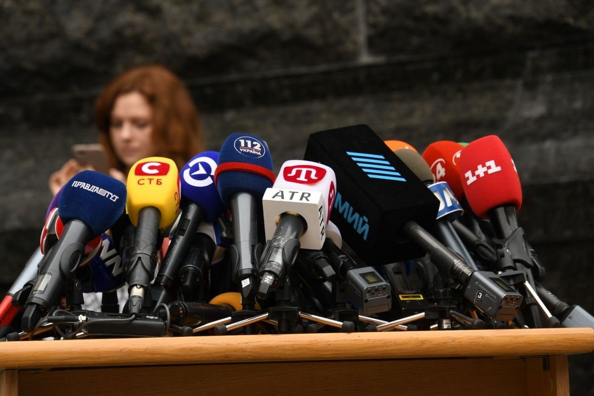 Several microphones arranged on a desk at a press event