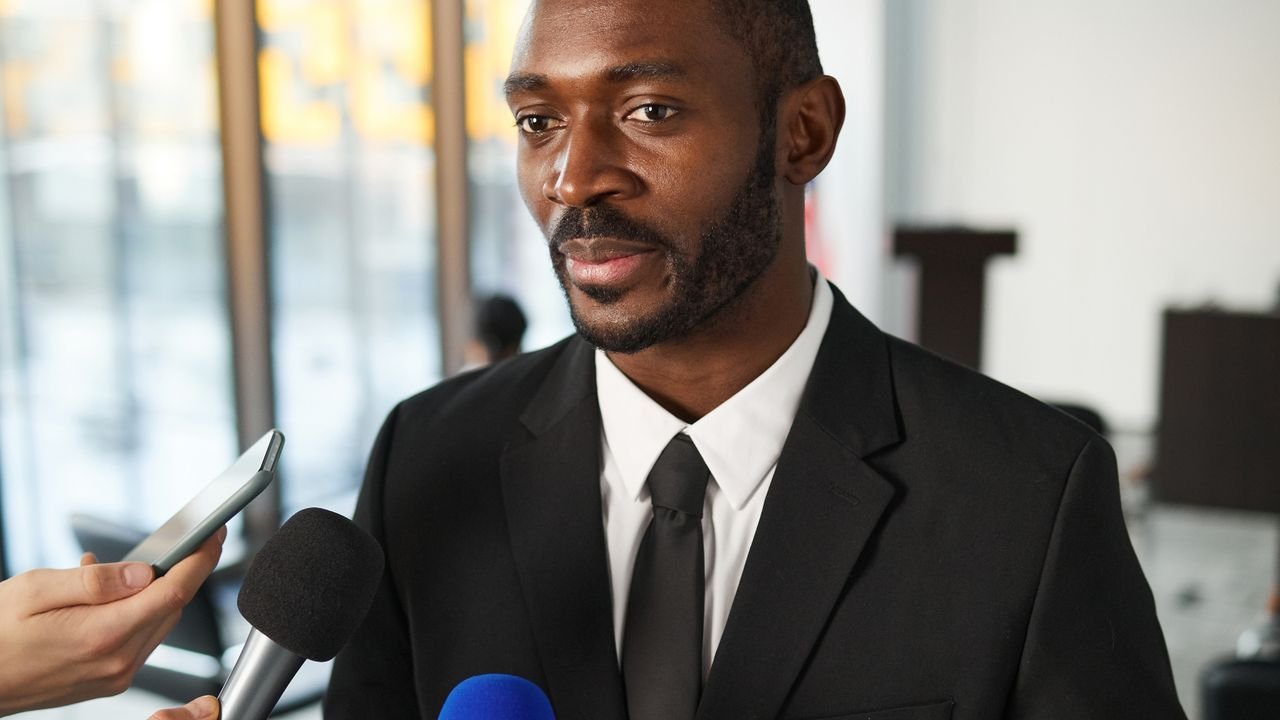 Businessman speaking to journalists holding microphones