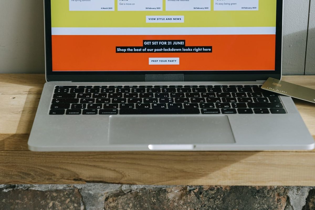 Laptop on a wooden shelf displaying a colorful online shopping page