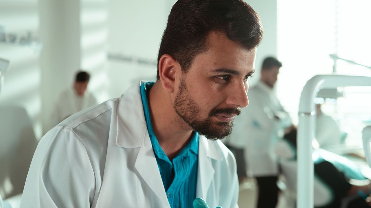 Dental professional in a white coat looking at a patient in a clinic