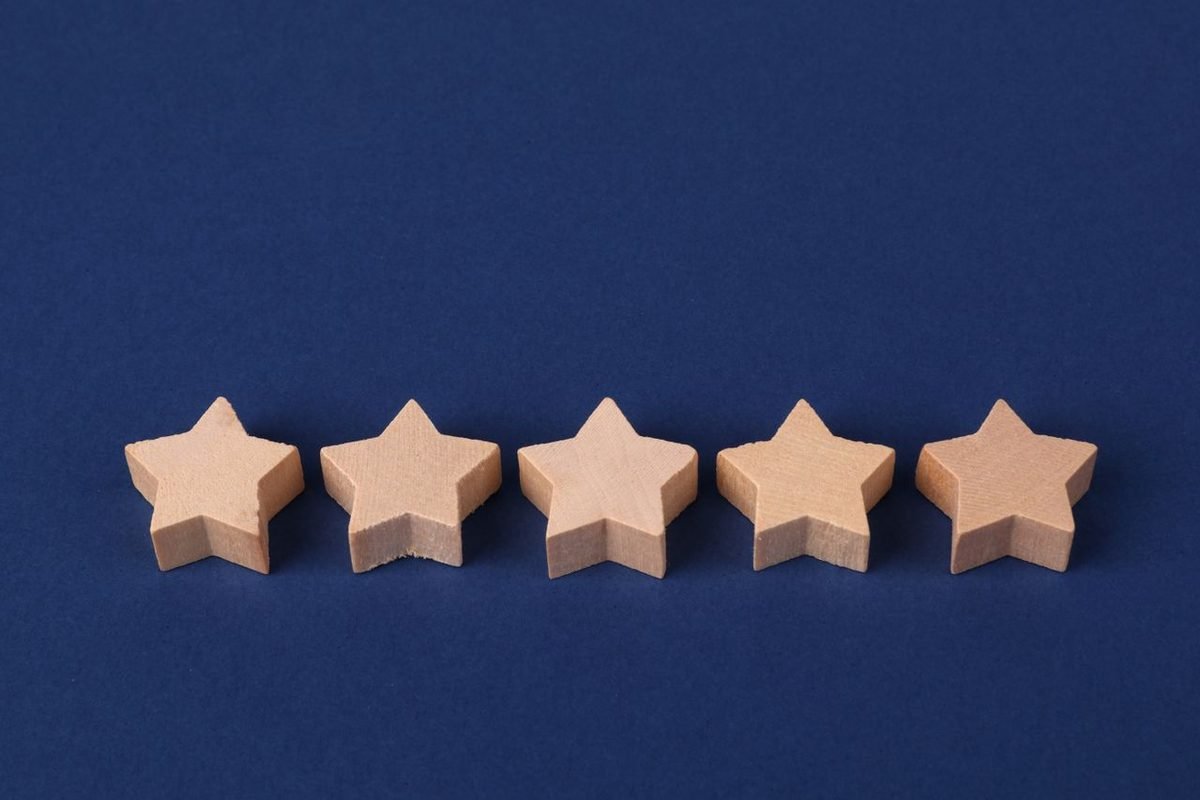 Five wooden stars in a row on a dark blue background representing a five-star rating