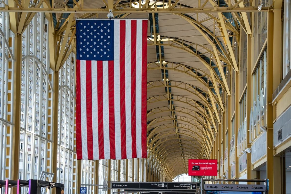 Large American flag hanging in a busy airport hall