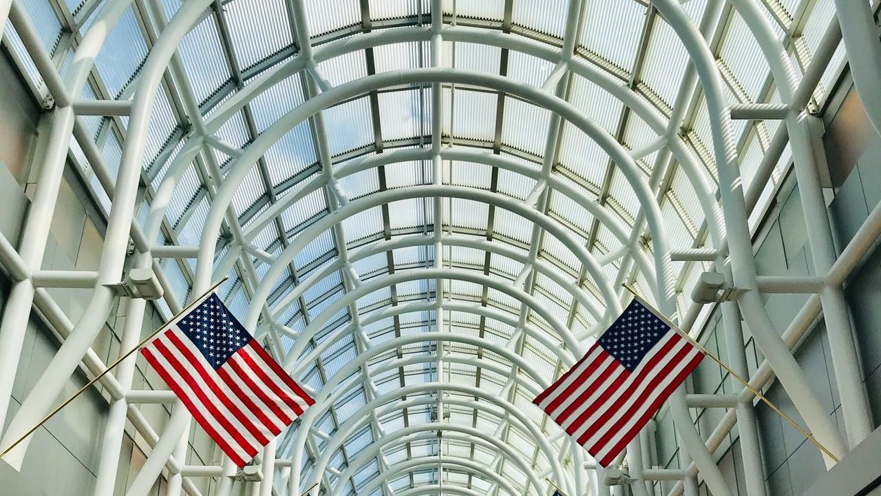 Glass-roofed airport terminal with flags hanging overhead