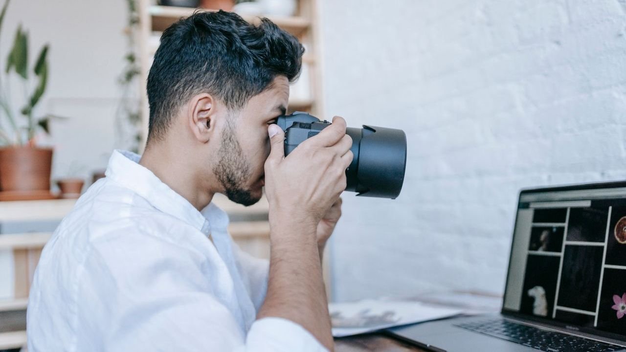 Photographer shooting with a camera beside a laptop showing a photo gallery
