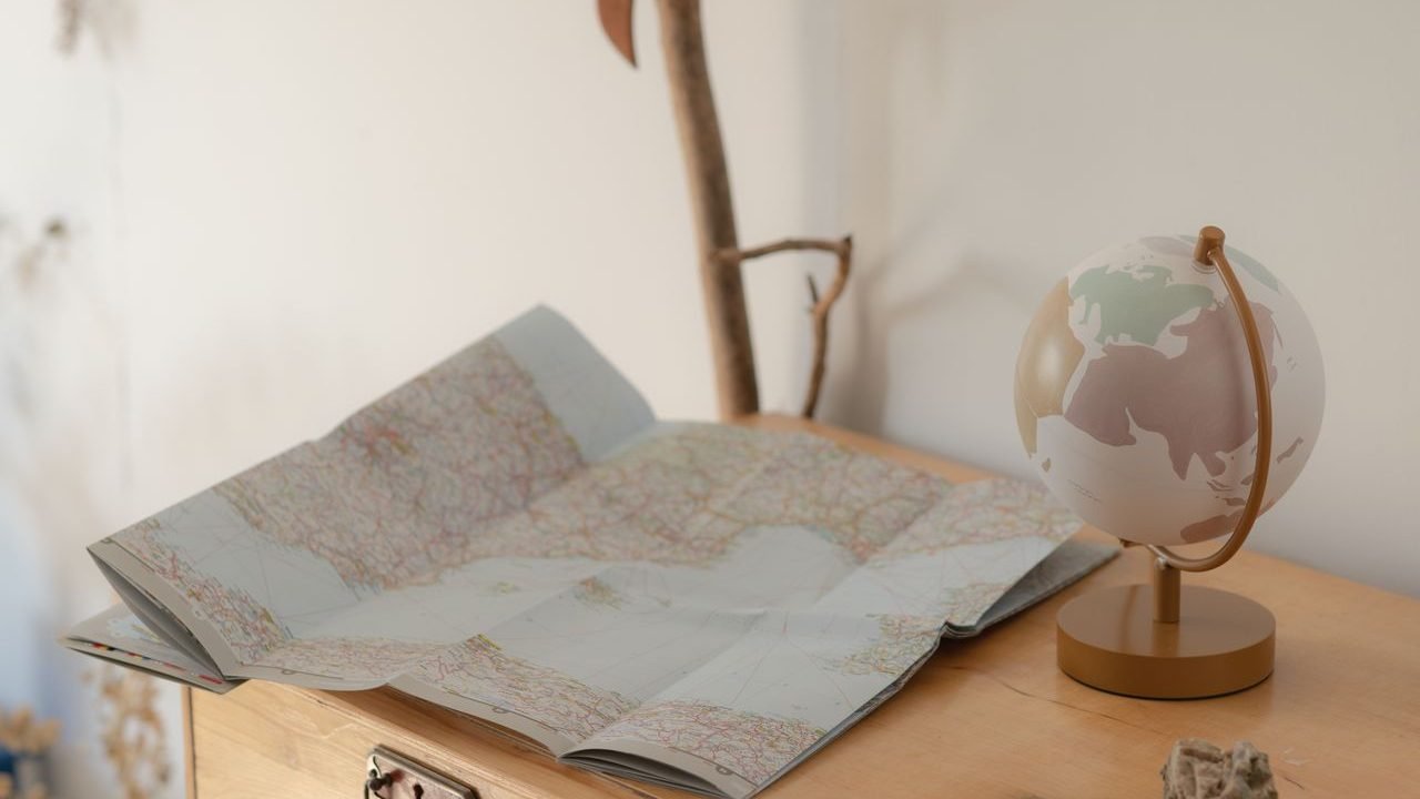 Folded road map and a small globe on a wooden shelf