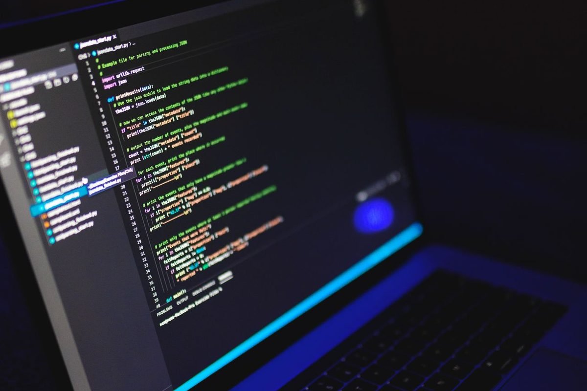 Laptop open to code at an angle in a dark workspace