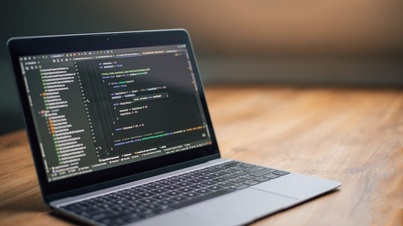 Open laptop with code on the screen on a wooden desk