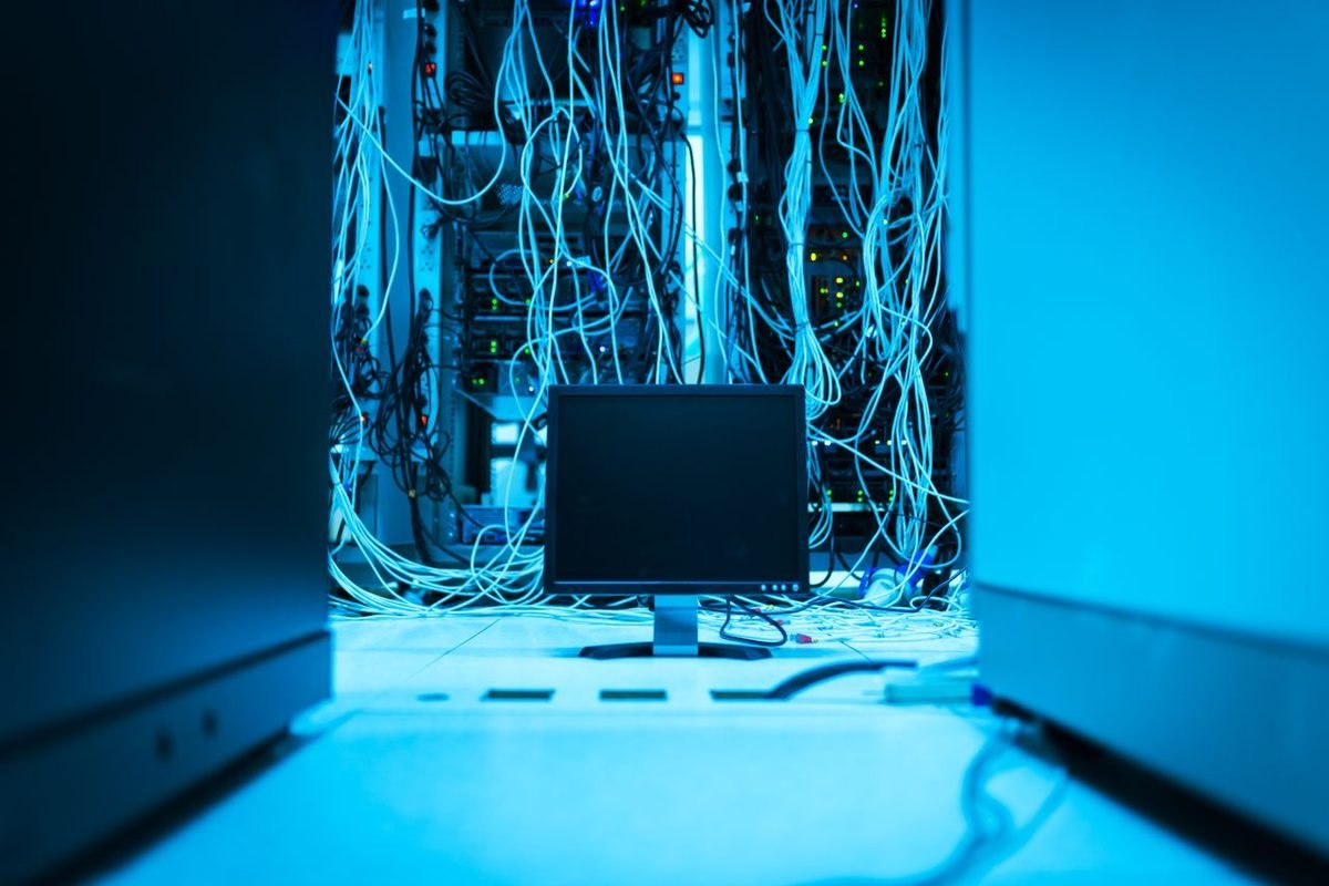 Tangle of network cables behind a monitor in a server room