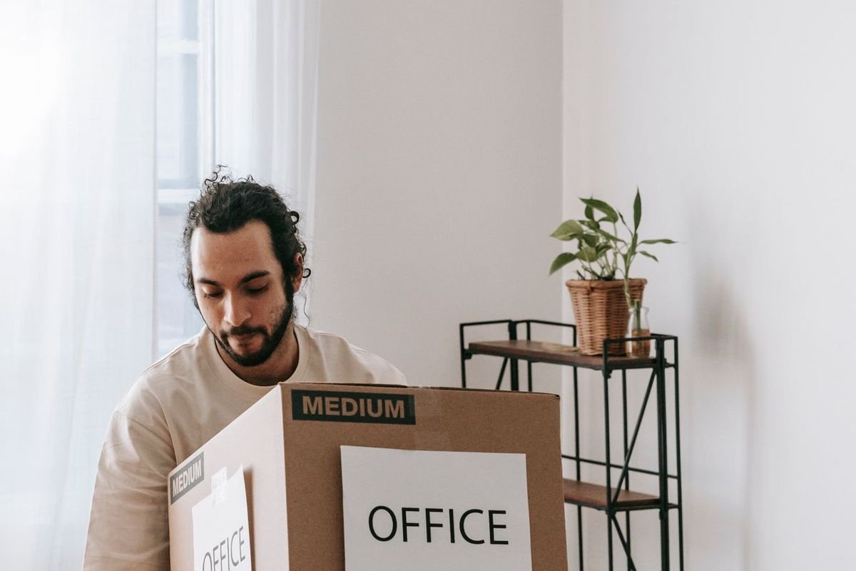 Man packing a cardboard box labeled Office
