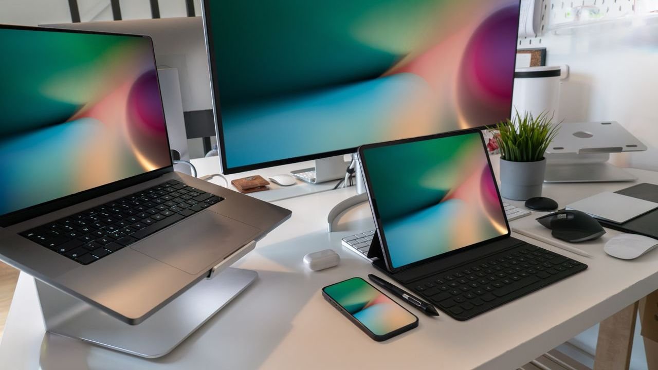 Desk with laptops, a monitor and a smartphone showing the same content