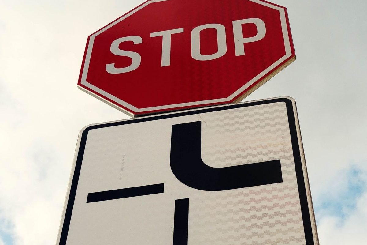 Stop sign above a road sign showing a junction
