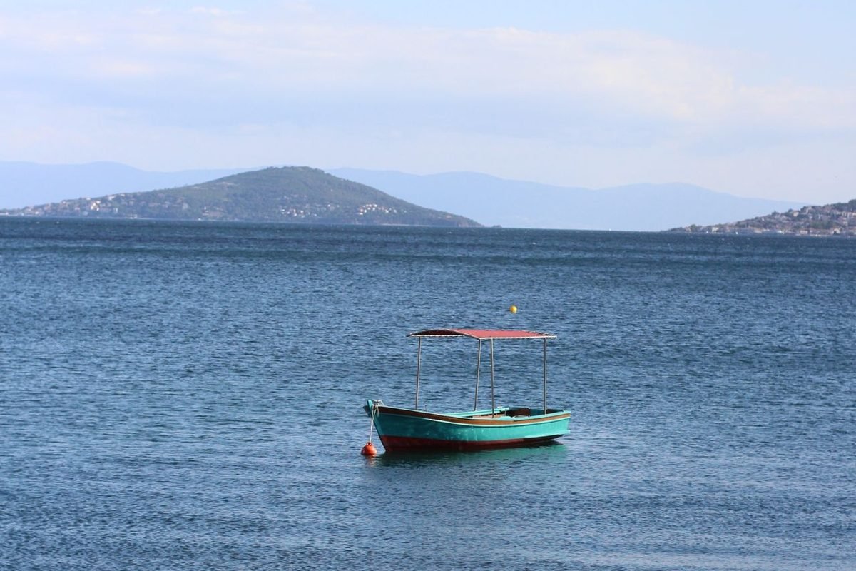Small boat alone on calm water with distant hills