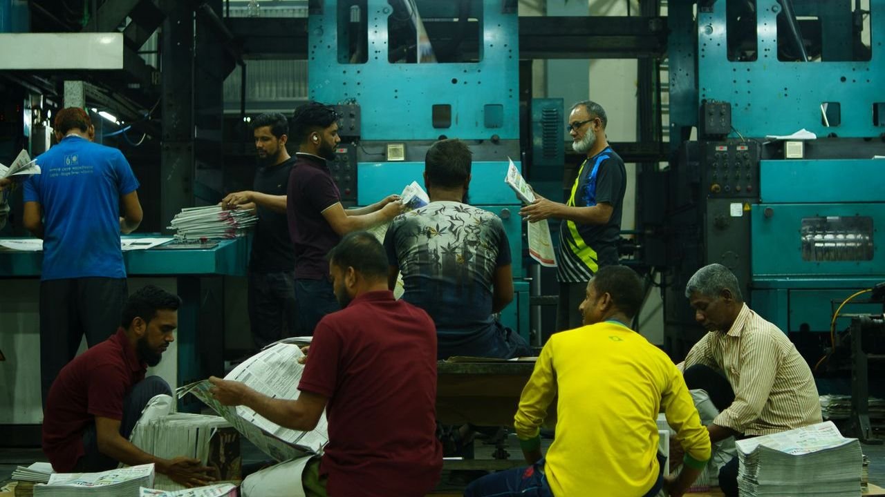 Team sorting printed newspapers in a large press room
