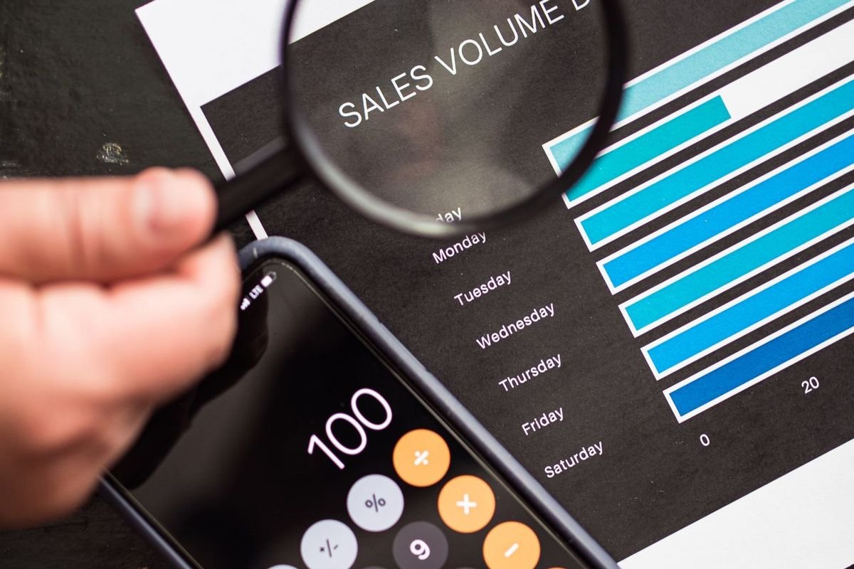 Magnifying glass held over a printed sales chart