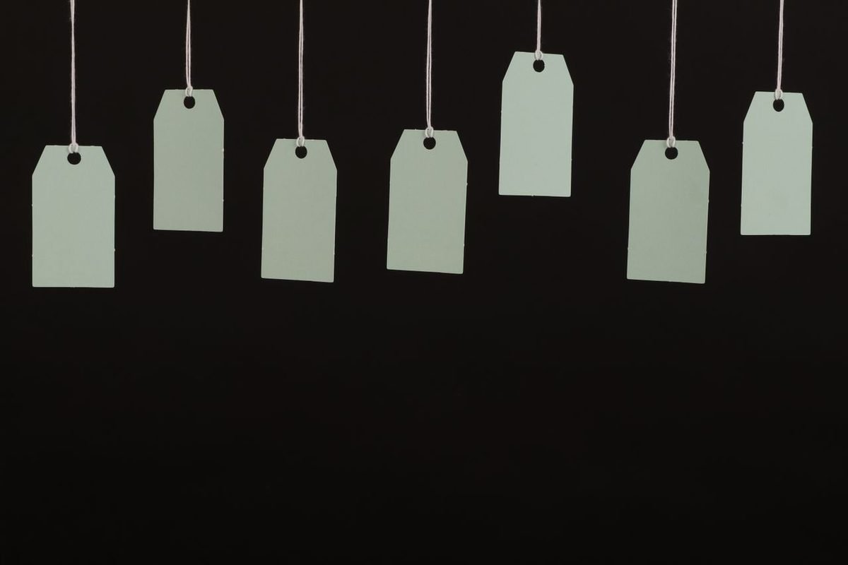 Blank paper tags hanging on strings against a black background
