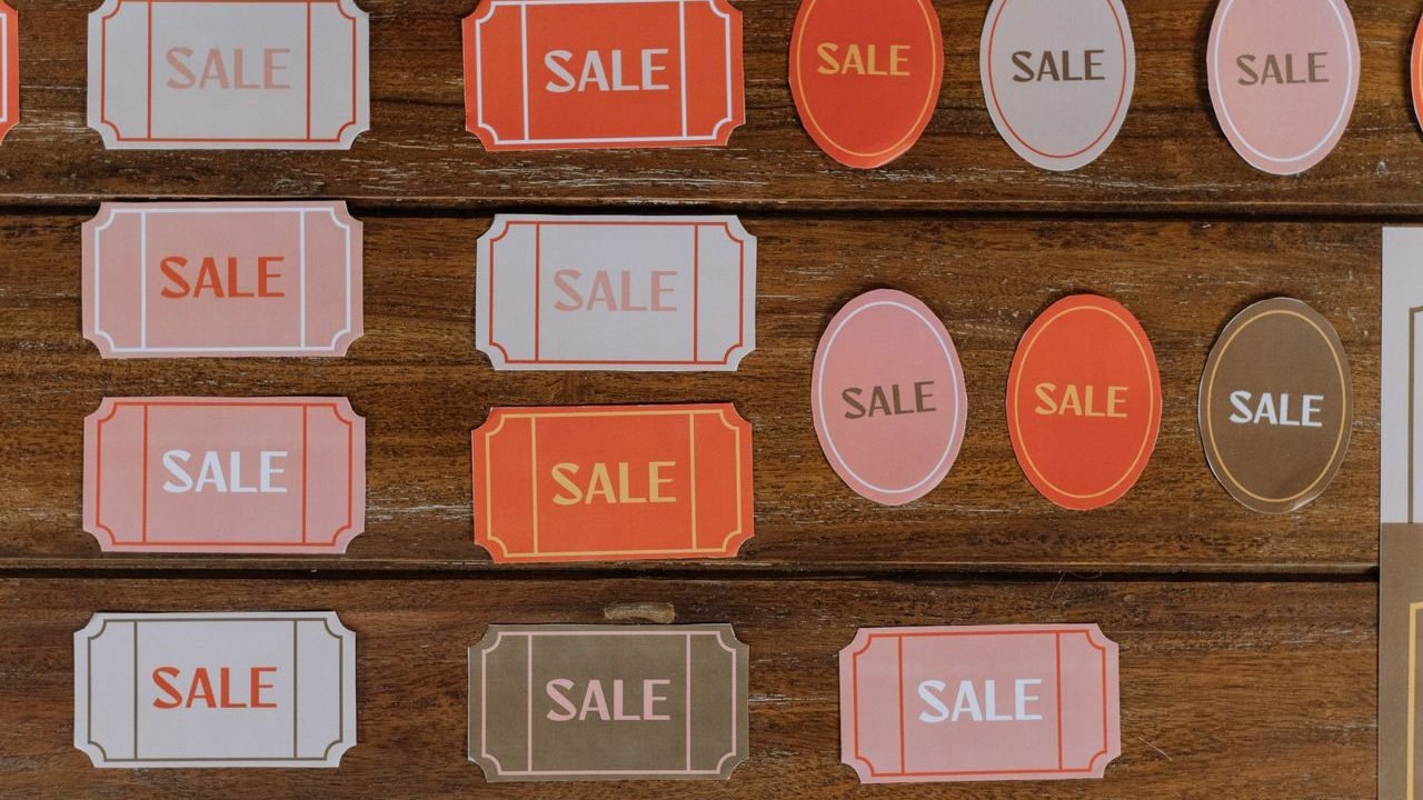 Rows of red and pink sale tags on a wooden surface