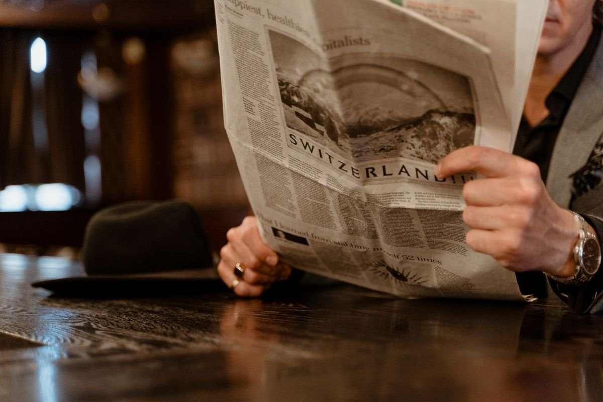 Man reading a newspaper in a cafe with the headline in focus